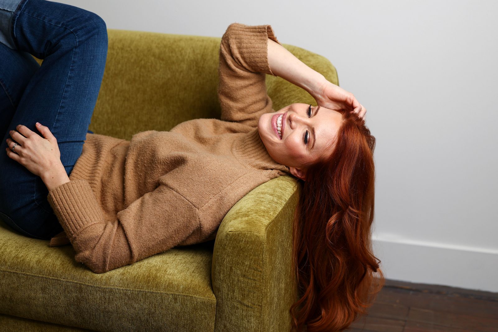 Redhead model on couch wearing Loxxie auburn extensions
