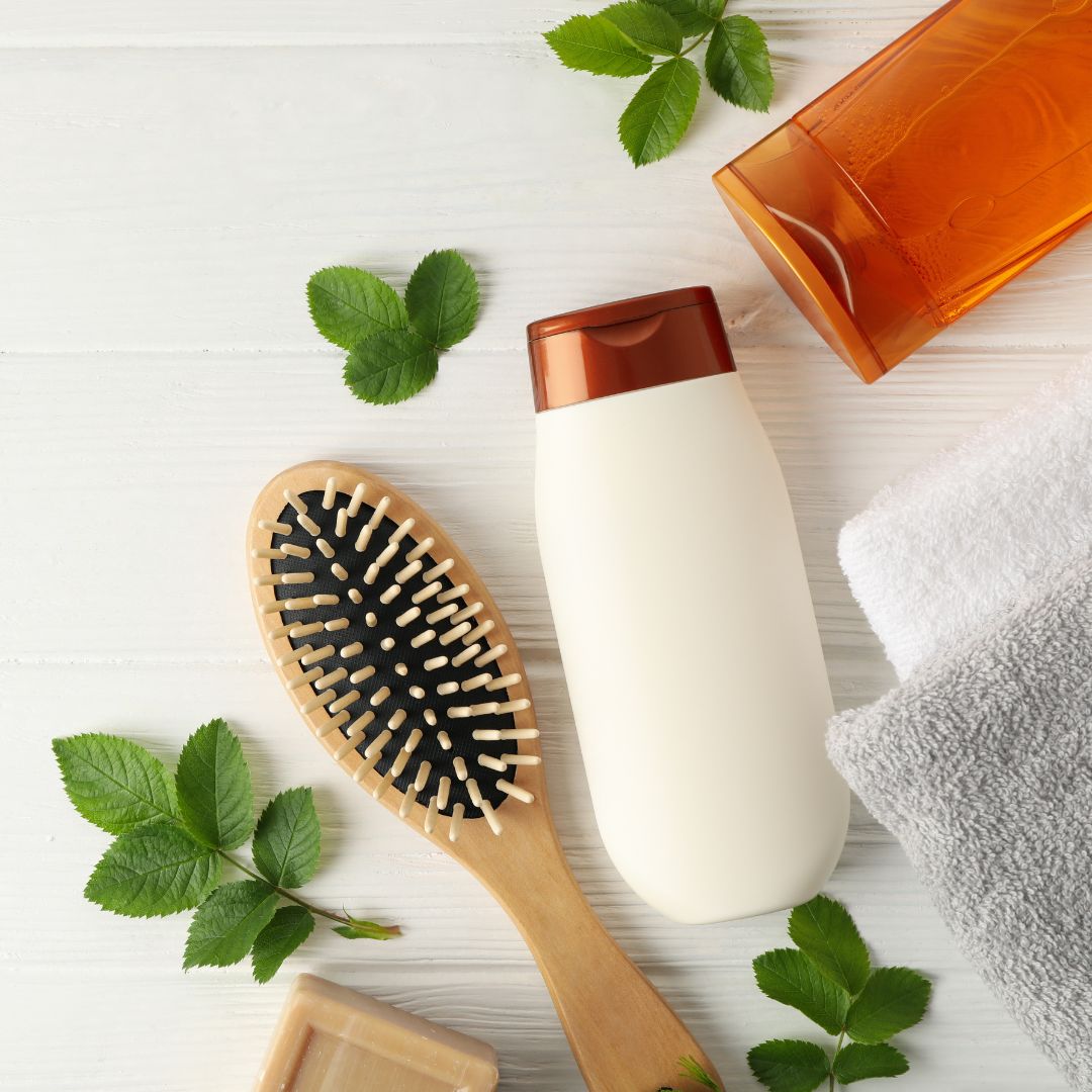 A Loxxie Hair shampoo bottle, a hairbrush, and two towels arranged neatly on a surface.