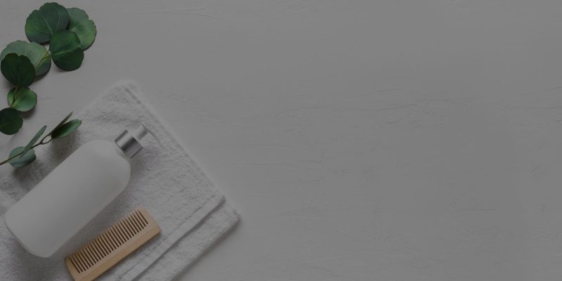 A white towel, Loxxie Hair shampoo bottle, and a brush arranged on a clean white surface.