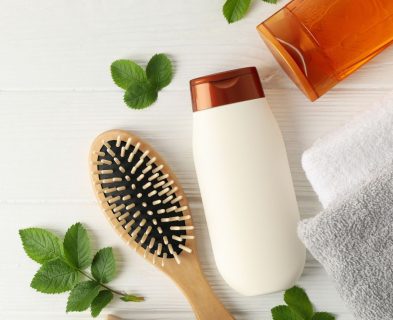 A Loxxie Hair shampoo bottle, a hairbrush, and two towels arranged neatly on a surface.