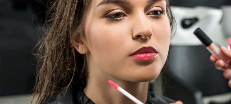 A woman receives makeup application from a professional artist at Loxxie Hair studio.
