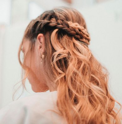 A woman with long red hair styled in a braid, showcasing Loxxie Hair products.